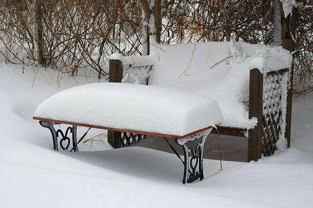 Eine mit Schnee bedeckte Gartenbank und Gartentisch